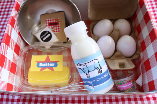 A basket containing ingredients for making slime, including butter, eggs, flour, sugar, milk, and sprinkles, displayed on a checkered background.
